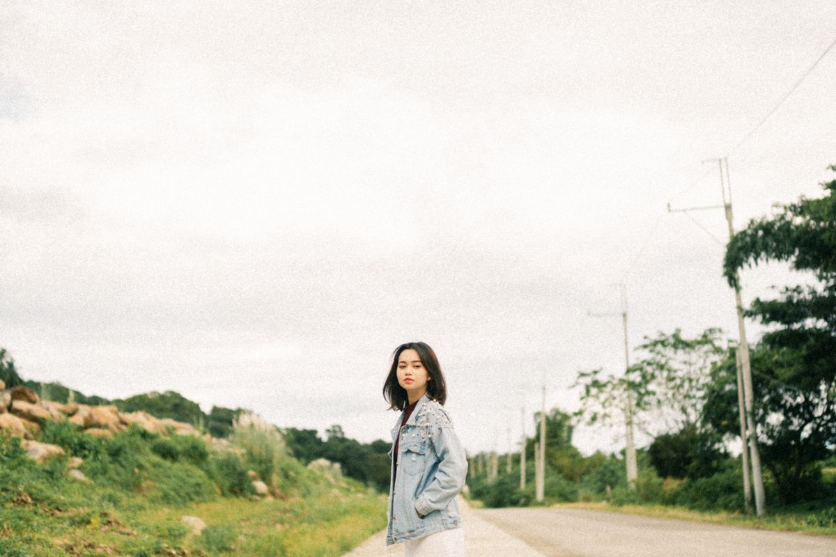 Young woman in Lucky Brand denim jacket by rural roadside